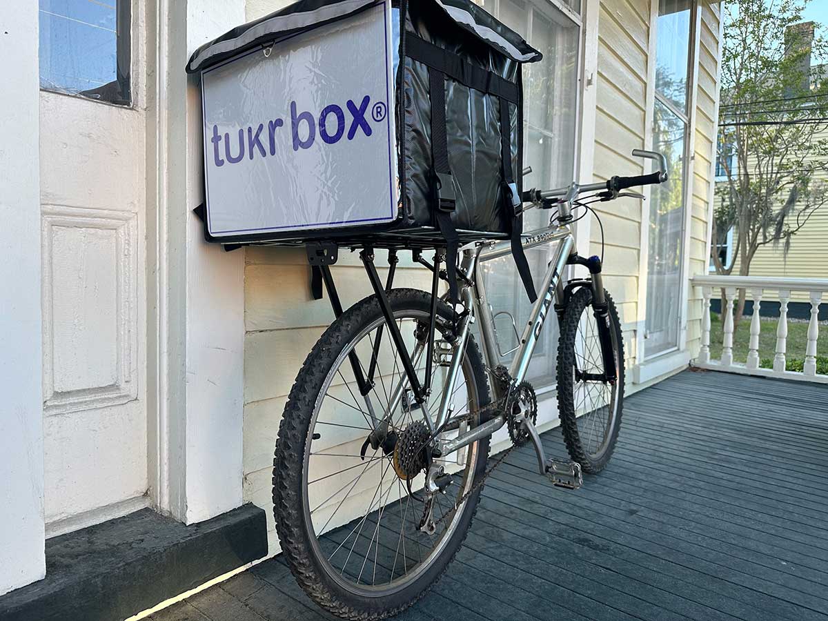 tukr box food delivery system hand-delivering a warm meal by bike to someone in need